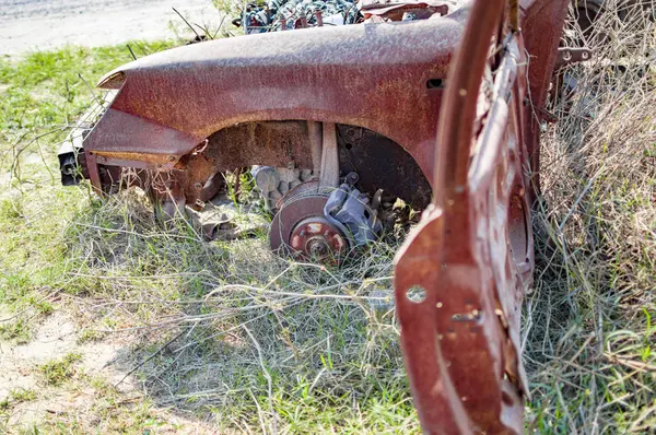 草の中に裸の車輪を持つ燃えた車 — ストック写真