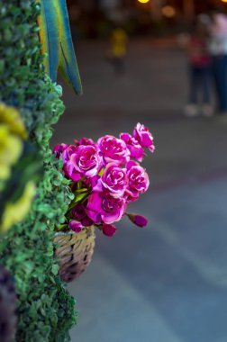 Duvardaki çimenler üzerinde pembe renklerde plastik çiçekler