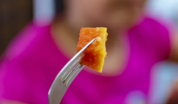 Eating papaya with fork being held in the hand
