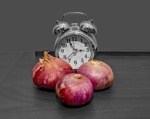 Cebolas e relógio na mesa — Fotografia de Stock