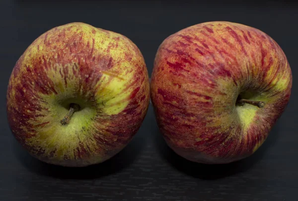 Two apples on black surface and of red and green color