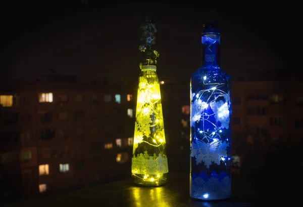 Gece şehir arka plan parlak sarı ve mavi cam şişe