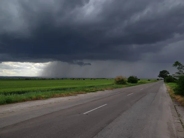 Boş yol ve yeşil alan üzerinde fırtınalı bulutlar