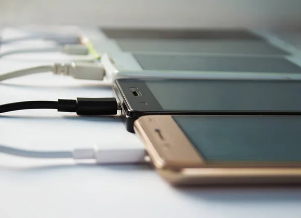 Çok fazla kablo ile şarj beyaz arka plan üzerinde akıllı telefonlar