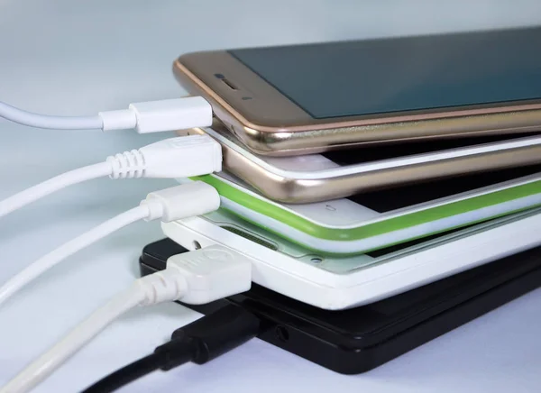 A pile of smartphones, charging through usb cables