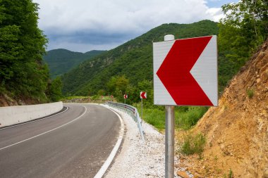 Dağ yolunda tehlikeli bir dönüş işareti var.