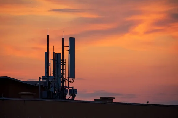 Phone tower antennas silhouette on sunset background