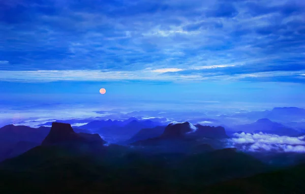 Sri Pada 'dan (Adam' s Peak) güzel manzara - sisli dağların gölgeli figürleri dramatik mavi gökyüzünün arka planına ve güneş doğarken dolunaya karşı, Sri Lanka Adası, Güney Asya