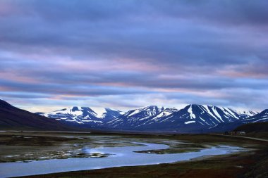 Muhteşem kutup manzarası - dramatik bulutlu gökyüzünün arka planında siyah dağ sıraları, su ve çorak zemin, Longyear 'ın kenar mahalleleri, Spitsbergen takımadaları (Svalbard Adası), Norveç, Grönland