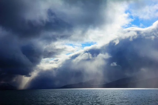 Barentsburg, Norveç, Svalbard, Spitsbergen adası, Grönland denizi yakınlarındaki fırtına bulutlarının arasından vurduğu, dramatik gökyüzü altında Istfjorden 'in karanlık sularının güzel manzarası.