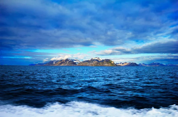 Bellsund, Spitsbergen (Svalbard Adası), Norveç, Grönland Denizi 'ndeki dramatik mavi gökyüzünün arka planında engebeli kar ve yosun kaplı engebeli kayalarla güzel manzara.