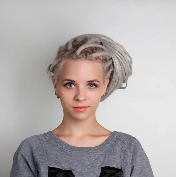 dreadlocks ve gri arka plan üzerinde mavi gözlü genç güzel pozitif beyaz kız