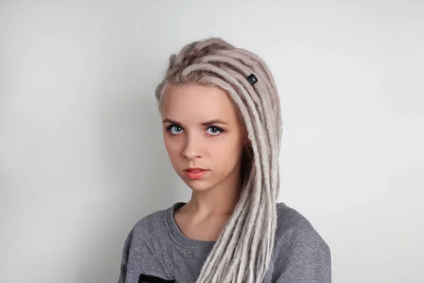 dreadlocks ve gri arka plan üzerinde mavi gözlü genç güzel pozitif beyaz kız
