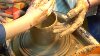 Potter'ın ona çanak çömlek çarkı ile çalışmaya yardımcı olmak için yol gösterici çocuğun el eller. Potter's tekerlek kil heykel küçük bir çocuk öğrenir