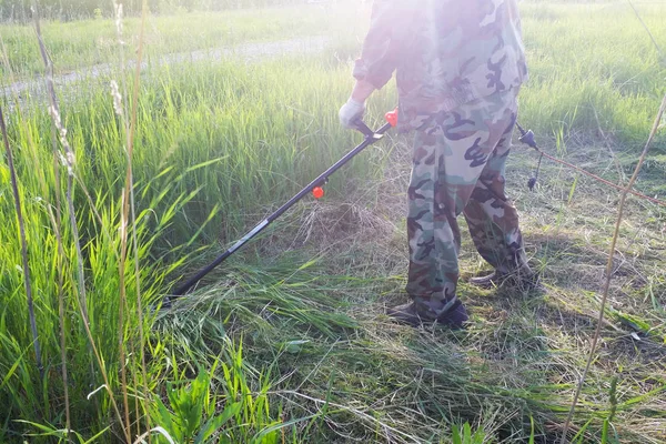 Working man mow high green grass with electric lawn mower