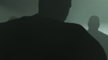 Karanlık siluetleri ile sorgu odası. Dedektif kelepçeli adam sorguluyor