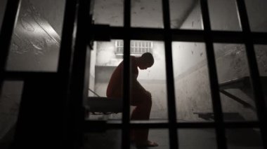 Depresif ceza eski grunge hapishane hücresinde parmaklıklar arkasında oturan.