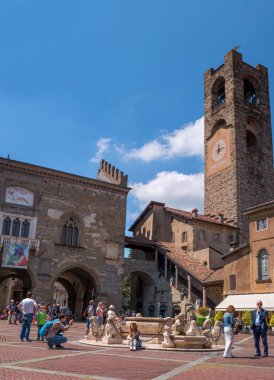 Bergamo, İtalya - 10 Mayıs 2018: Üst şehirde eski Meydanı. Bergamo de bir saat ile Ortaçağ çan kulesi. Turistler, Çeşme meydanında. Eski şehrin antik mimari