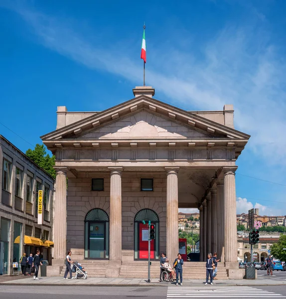 Bérgamo, Italia - 10 de mayo de 2018: Un antiguo edificio con columnas en la plaza del puerto de Nuova. Pasarela. En el semáforo rojo. Una persona con discapacidad en silla de ruedas — Foto de Stock