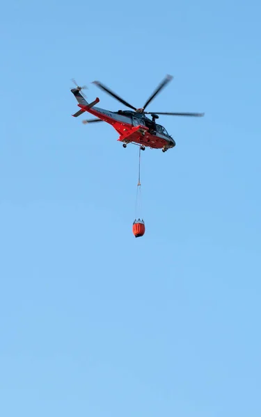 Narva, Estonsko - 27 července 2018: vrtulník hasičů s ohněm bojovat kbelík se účastní hašení požáru. Vrtulníku Agustawestland Aw139 vybavené pro hasiče — Stock fotografie