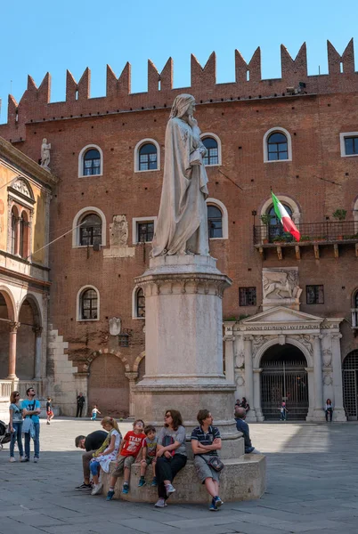 Verona, Itália - 06 de maio de 2018: Monumento de Dante Alighieri na Piazza della Signoria em Verona. Ao pé do monumento sentar turistas. Ao fundo, a bandeira da Itália e o leão veneziano — Fotografia de Stock