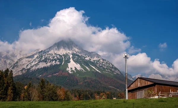 Paysage alpin par une journée ensoleillée. Scène d'automne colorée. Montagne et un énorme nuage au-dessus. Au premier plan se trouve une tour de relais et un hangar alpin. Fond naturel incroyable. Tyrol du Sud Autriche — Photo