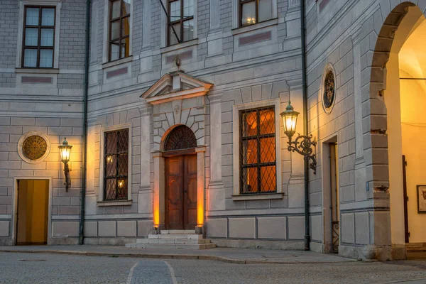 Fragment of the Munich residence. Lit wall lamp. Arched windows are lit