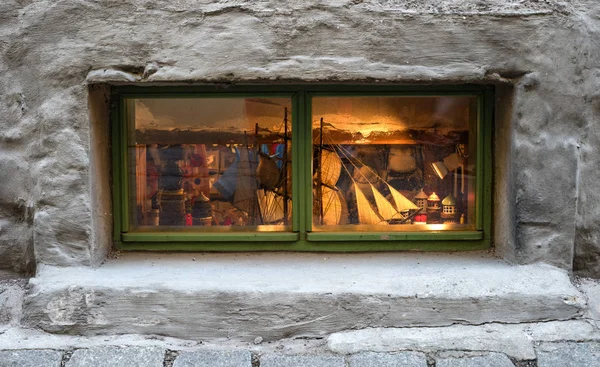 Gift shop window. You can see retro toys, a model of a sailing ship. The window is highlighted in yellow. The window is small, near the ground — Stock Photo, Image