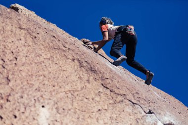 Petite asian woman rock climbing outdoors ascends a sloped stone face with no safety gear clipart