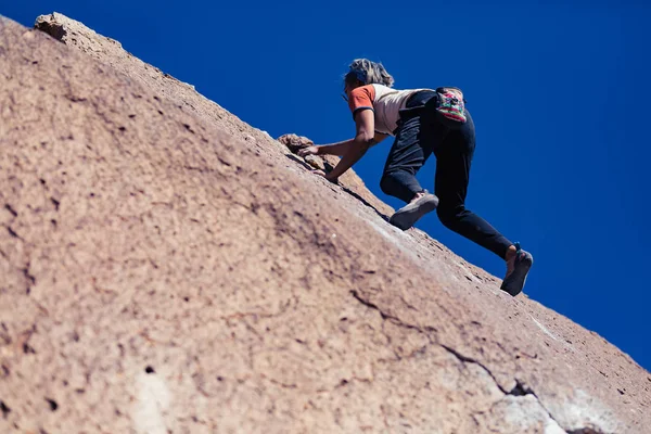 小柄なアジアの女性ロック クライミング安全装置もないと傾斜の石の顔を登る屋外 — ストック写真