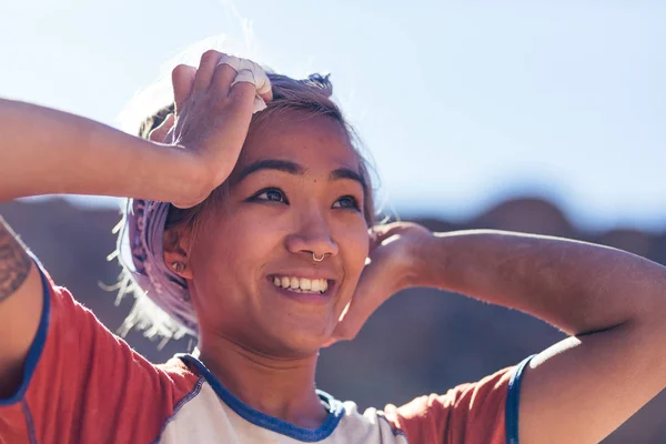 年轻的亚洲妇女在户外微笑着看朋友攀岩在沙漠中 — 图库照片