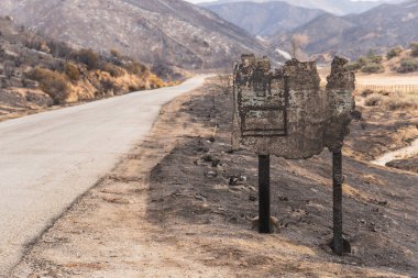 Destroyed wooden sign along road damaged by the Thomas Fire along Highway 33 in Ojai, California clipart