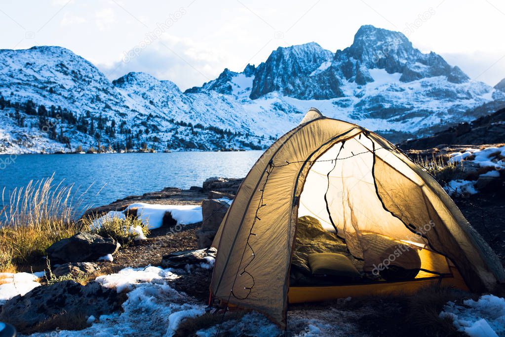 Yellow tent with string lights at sunset under Banner Peak in the Ansel Adams wilderness