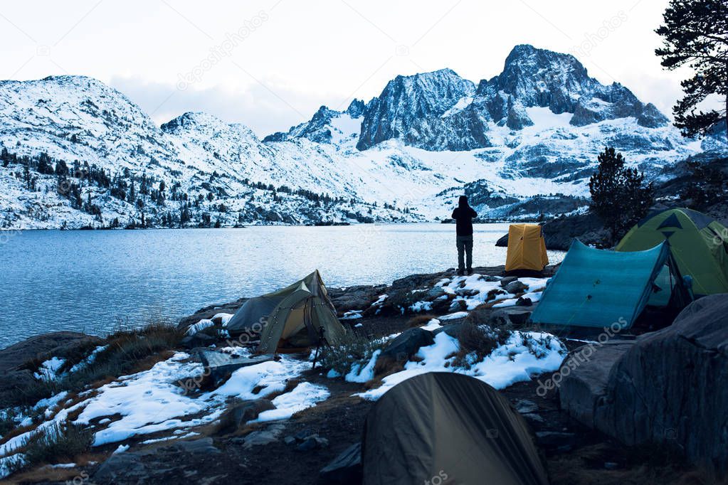 Backpacker and tents on the shore of Garnet Lake at sunset in the Ansel Adams wilderness