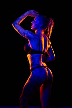 Dövmeli kafkas kadın kaslı ve yağlı cilt pozlar renkli ışıklar altında