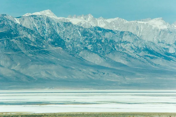 Mount Whitney with snow and a salt pond below in the foreground