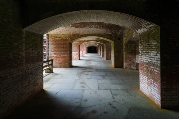 Masonry arched hallway stretching away into the darkness. Typical of forts and prisons of the Victorian period