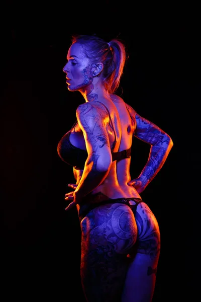 Мускулистая Белая Женщина Татуировками Смазанной Кожей Позирует Цветными Огнями — стоковое фото