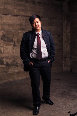 Young transgender man in formal clothing poses in a grungy urban location clipart