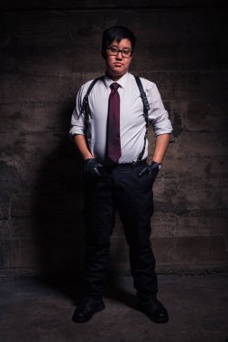 Young transgender man in semi formal clothing with a bondage style leather harness poses in a grungy urban location clipart