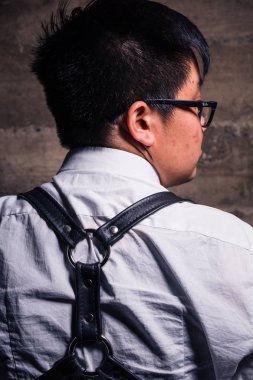 Genç travesti adam yarı resmi giyim bir esaret stil deri koşum takımı ile bir grungy kentsel konumda teşkil etmektedir.