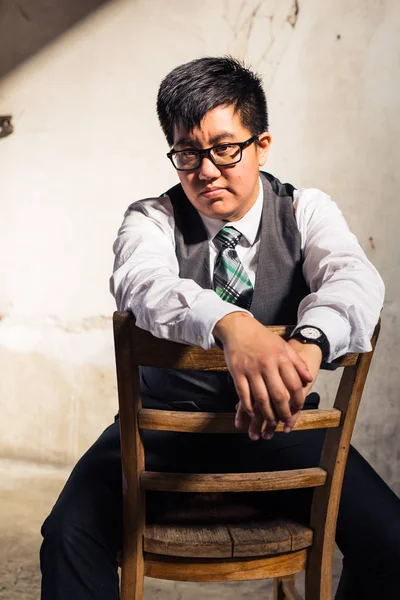 Young transgender man in formal clothing poses in a grungy urban location