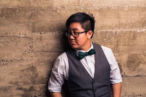 Young transgender man in formal clothing poses in a grungy urban location