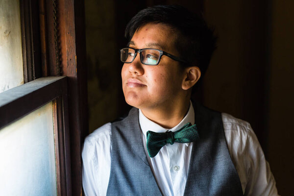 Young transgender man in formal clothing poses in a grungy urban location