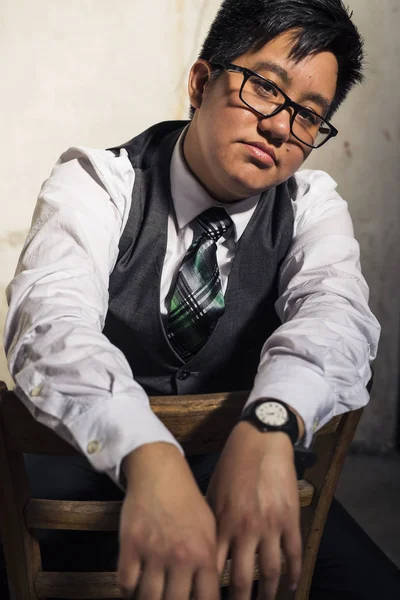Transgender man in shirt and tie poses in a grungy location