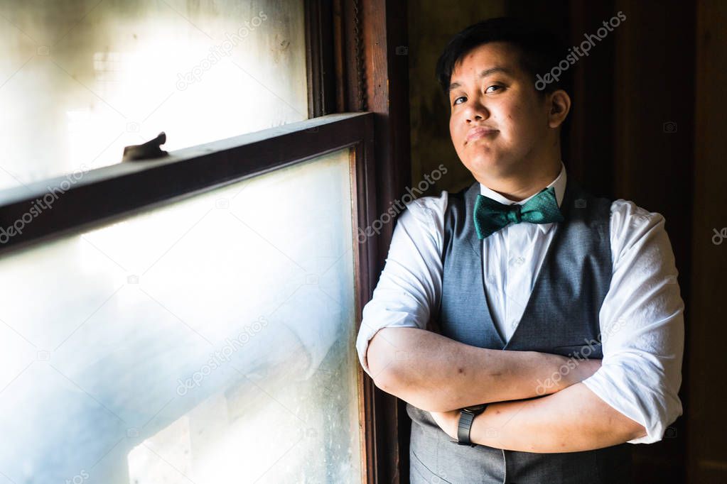 Young transgender man in formal clothing poses in a grungy urban location