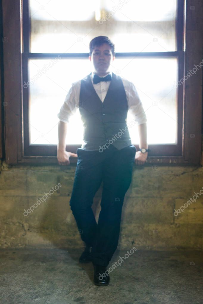 Young transgender man in formal clothing poses in a grungy urban location