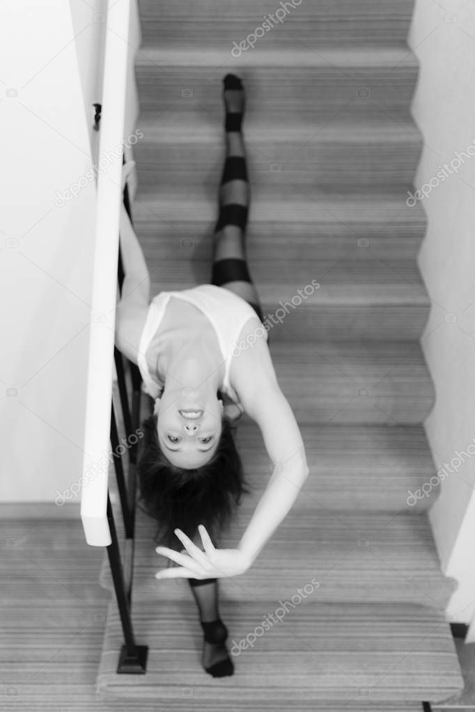 Middle aged caucasian woman in dance wear poses on a set of stairs