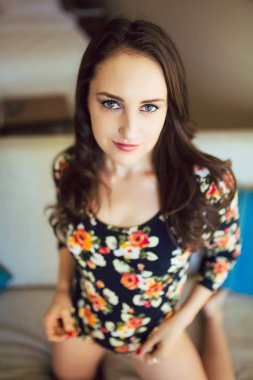 Koltukta genç kafkas kadın çiçek tek parça streç giysi ve çıplak bacak reclines