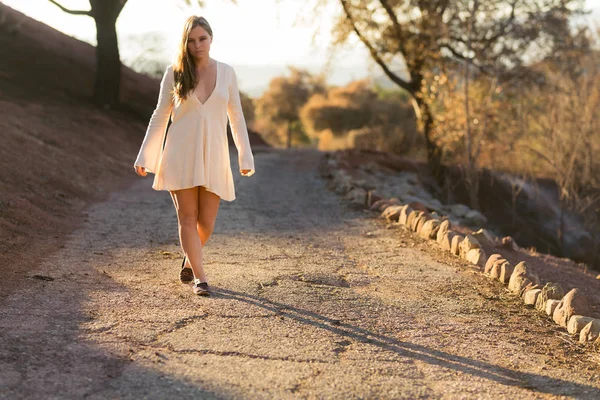 Nuori Sekarotuinen Nainen Valkoisessa Mekossa Kävelee Pitkin Tietä Auringonnousun Aikaan — kuvapankkivalokuva